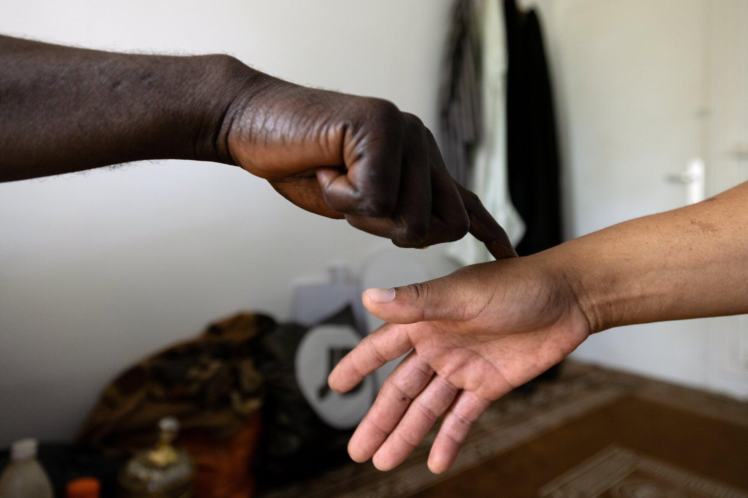 El curandero africano Sheikh Issa prueba la mano de su cliente Raymond antes de una consulta.