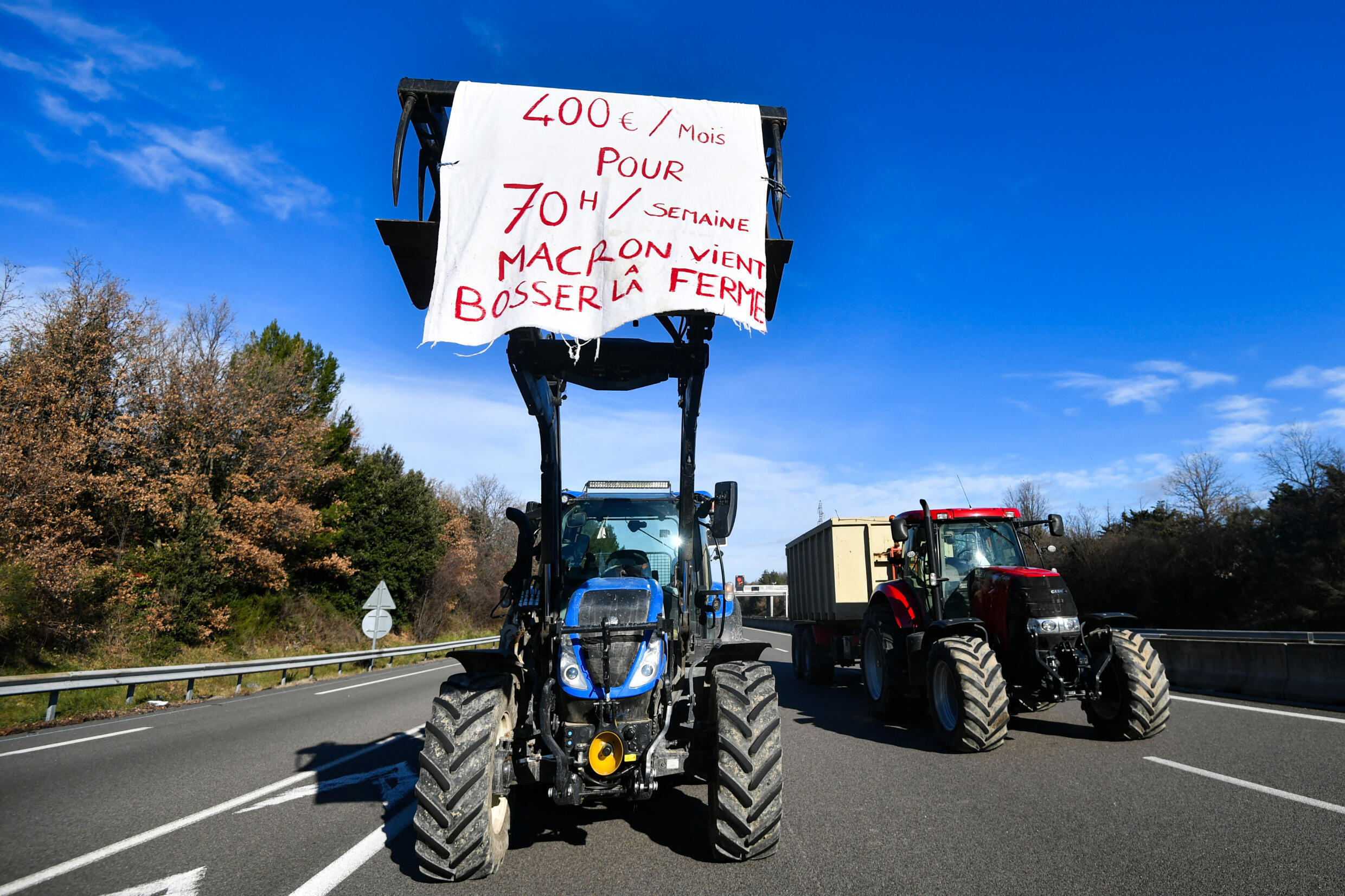 Un tractor lleva una pancarta que indica "400 euros al mes, 70 horas a la semana, Macron viene a trabajar a la granja" en el sureste de Francia el 24 de enero de 2024.