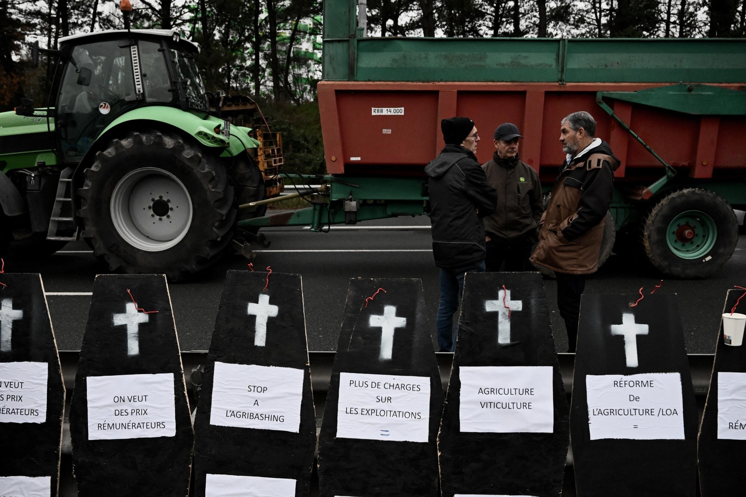 Los agricultores se encuentran cerca de ataúdes falsos mientras bloquean una carretera alrededor de Burdeos, suroeste de Francia, el 24 de enero de 2024.