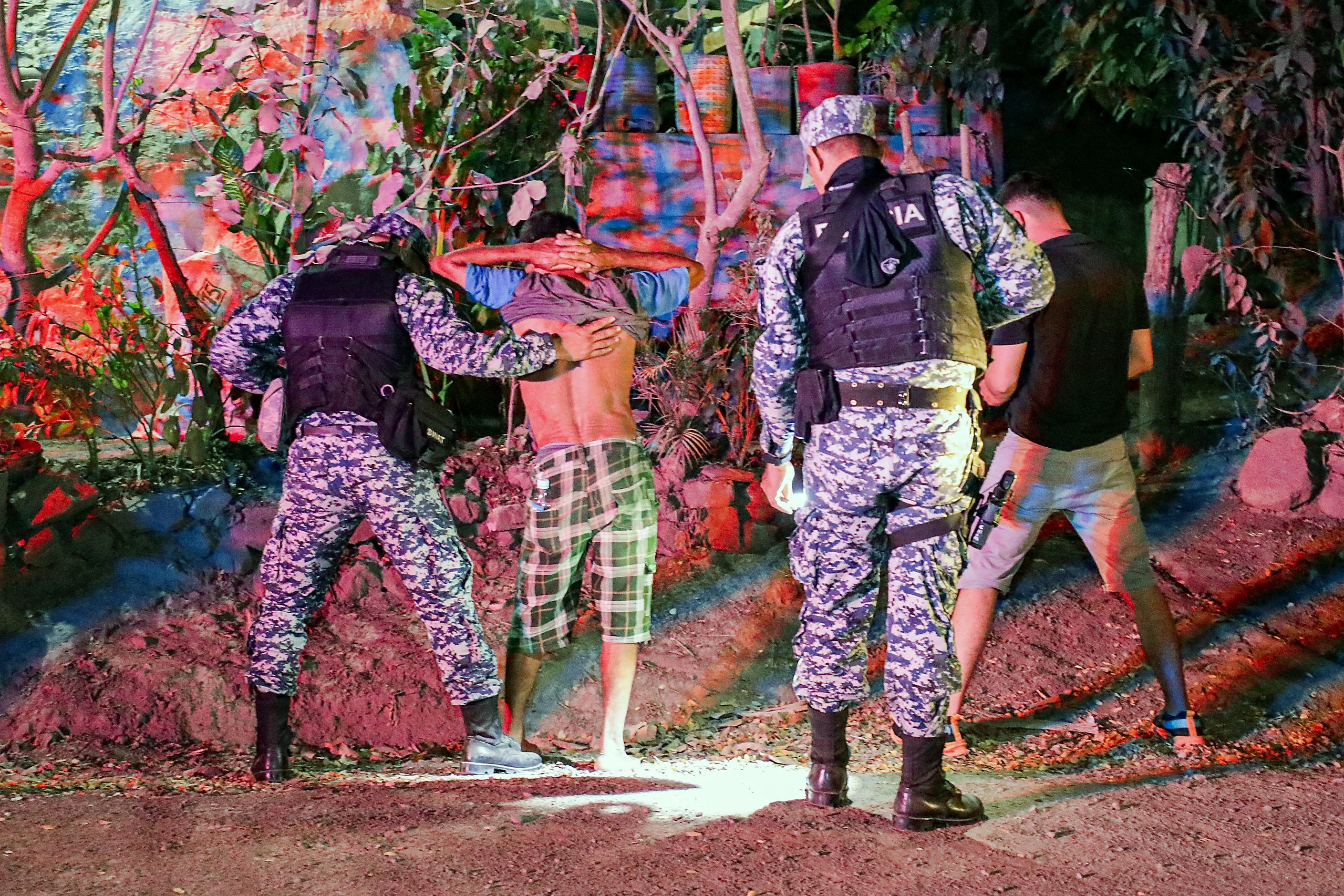 Esta imagen proporcionada el 25 de marzo de 2024 por la oficina de prensa presidencial de El Salvador muestra a las fuerzas de seguridad registrando a dos sospechosos durante un operativo.